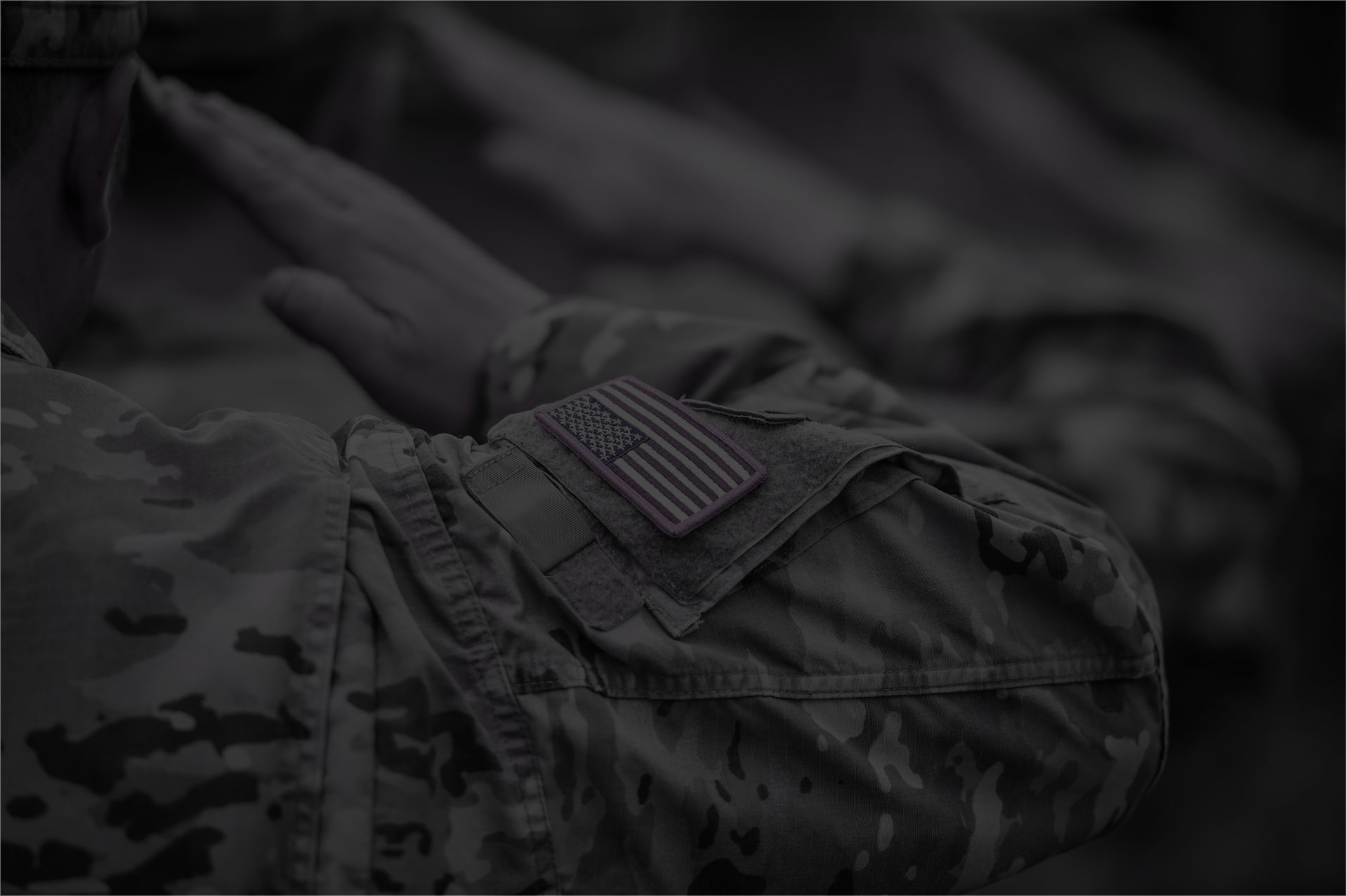 Soldier saluting with American flag patch in subdued colors