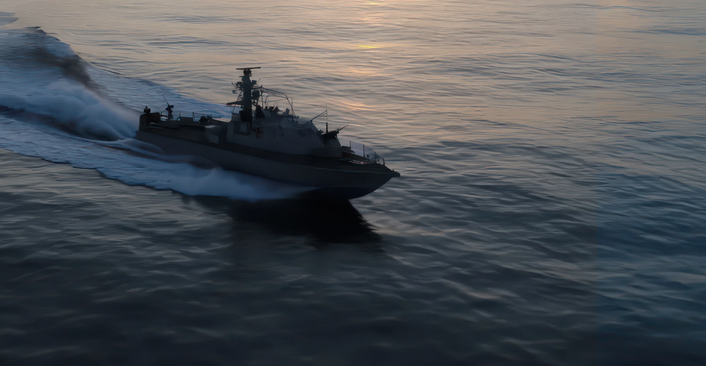 Military patrol boat speeding across calm sea water during sunset or sunrise.