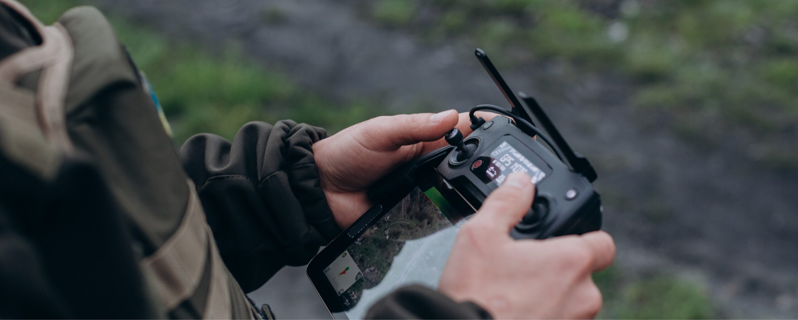 Person holding and operating a DJI remote controller outdoors, focusing on controlling a drone.